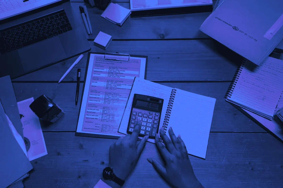 Calculatrice et documents sur un bureau de travail pour calculer le coût d&rsquo;un commercial salarié