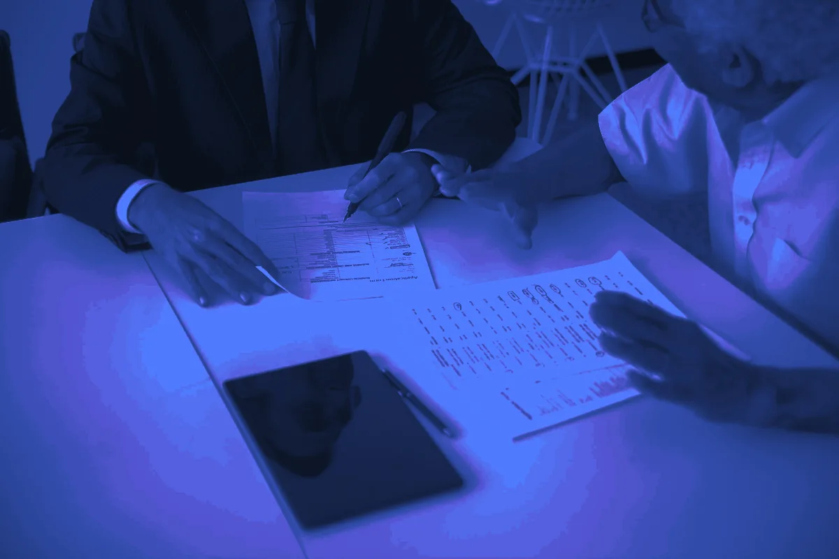 Conseiller et client échangeant autour de documents et d’une tablette, un rendez-vous type issu de leads assurance