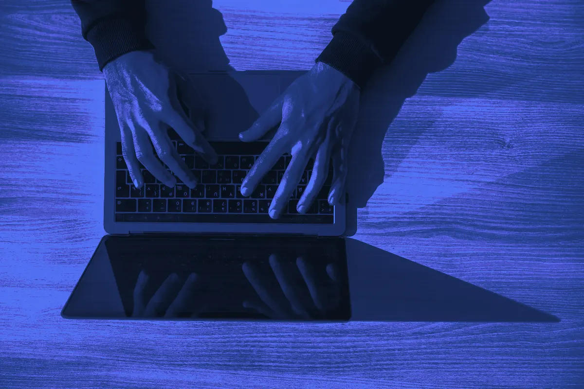 Mains tapant sur le clavier d’un ordinateur portable vu du dessus, en train de rédiger un mail de relance à un prospect