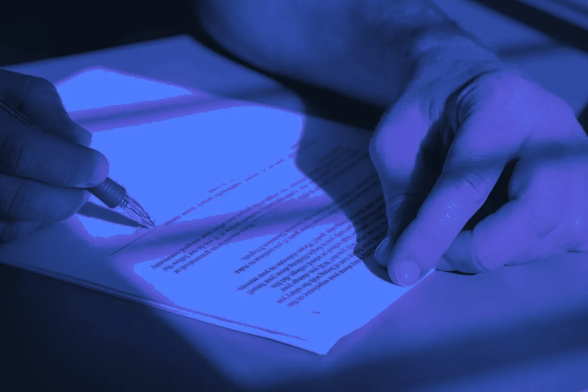 Main tenant un stylo au-dessus d’un document à signer, l’étape que vise la relance d’un devis envoyé au client